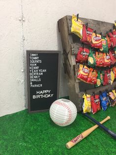 a baseball bat, ball and candy bar display on fake grass in front of a sign