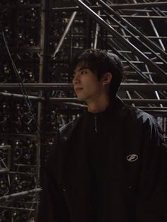 a young man standing in front of a bunch of metal pipes with wires all over them