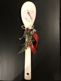 a wooden spoon with a bird on it and christmas decorations hanging from the top of it