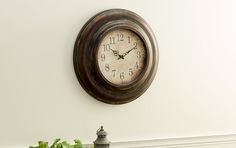 a clock is on the wall next to a potted plant