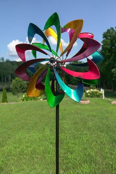 a colorful wind spin sitting on top of a lush green field