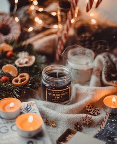 candles, cookies and other holiday decorations on a blanket with lights in the background at christmas time