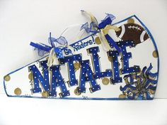 a football themed name sign hanging from the side of a white wall with blue and gold polka dots