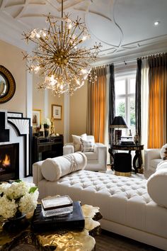 a living room filled with white furniture and a chandelier hanging from the ceiling