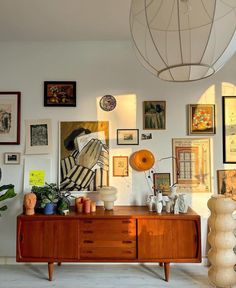 a room filled with lots of art and pictures on the wall next to a dresser