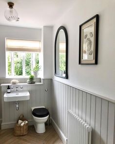 a white toilet sitting next to a sink in a bathroom under two framed pictures on the wall