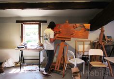 a man is painting on an easel in his studio