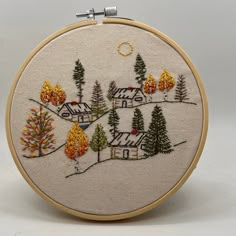 an embroidery pattern with houses and trees in the woods, on a white background that is stitched together