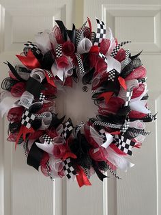 a red, white and black wreath hanging on the front door with checkered ribbon