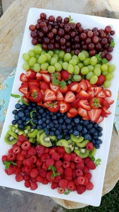 grapes, strawberries, and kiwis are arranged on a white platter