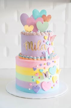 a multi - layer cake with hearts and rainbows on the top is decorated in pastel colors