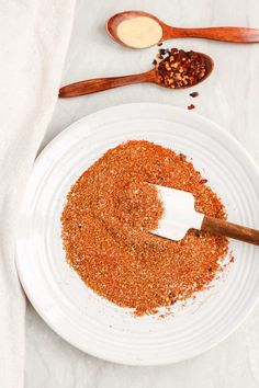 a white plate topped with spices next to wooden spoons