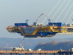 a large crane is on the side of a bridge