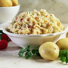 a bowl filled with potato salad next to some vegetables