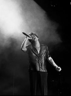 a man standing on top of a stage holding a microphone in front of his face