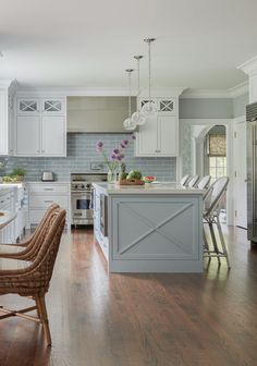 a large kitchen with white cabinets and wood flooring, along with an island in the middle