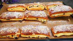 a tray filled with lots of pastry covered in powdered sugar and almond toppings