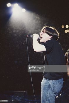 a man singing into a microphone in front of an audience at a concert stock photo