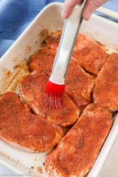 someone using a brush to brush up some food in a pan with sauce on it