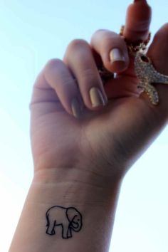 a woman's wrist with a small elephant tattoo on the left side of her arm