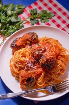 spaghetti with meatballs and tomato sauce on a white plate