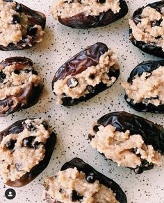 an assortment of stuffed dates on a white plate with brown sugar and raisins