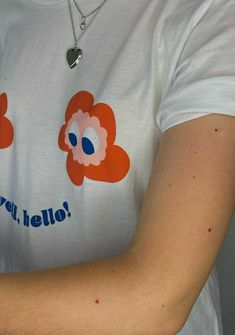 a person wearing a white t - shirt with red and blue flowers on it's arm