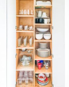 an open cabinet filled with dishes and glasses