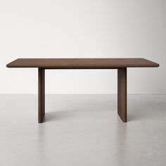 a wooden table sitting on top of a cement floor next to a white wall in an empty room