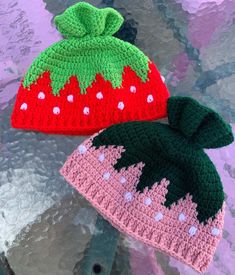 two crocheted hats sitting next to each other on top of a metal table