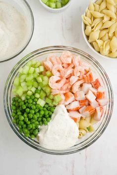 ingredients to make shrimp pasta in bowls on a white counter top, including peas, celery and carrots