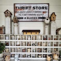 there are many bird houses on the shelves in this room and one has a sign above it that says thrift store