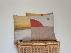 two pillows sitting on top of a wicker basket