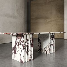 two marble tables sitting next to each other on top of cement flooring in an empty room