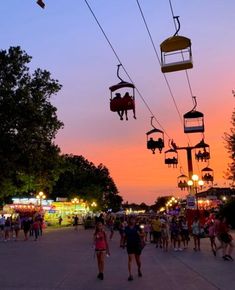 many people are walking down the street at dusk with their ski lifts above them