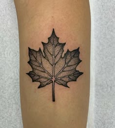 a black and white photo of a leaf tattoo on the right leg, it looks like an inked maple leaf