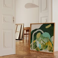 an empty room with two chairs and a painting on the floor in front of it