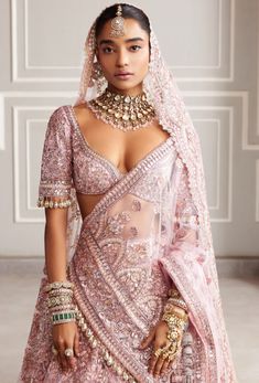 a woman in a pink bridal gown with jewelry on her neck and chest, standing next