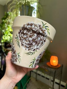 a hand holding up a cup with flowers painted on it