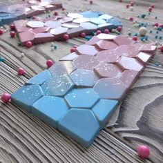 there are many different colored tiles on the table with beads around them and one is pink, blue, and white