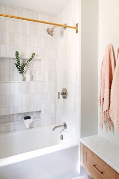 a bathroom with a bathtub, towel rack and wooden cabinet in the shower area