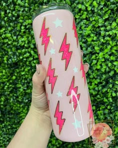 a hand holding a pink tumbler cup with stars and lightnings on the side