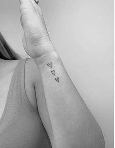 a woman's arm with two hearts on it and one heart in the middle