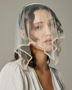 a woman wearing a veil with pearls on it