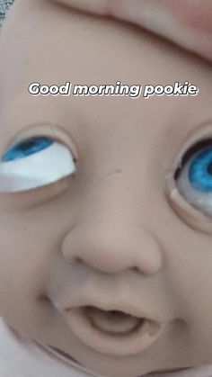 a baby doll with blue eyes has the words good morning pookiie on it's forehead