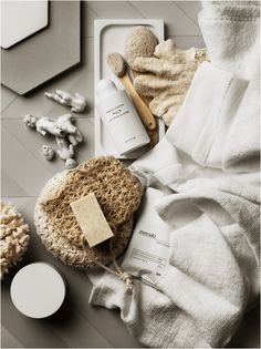 an assortment of personal care items laid out on top of a table with towels and soaps