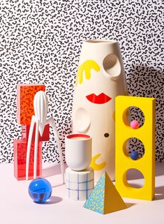 an assortment of colorful objects sitting on top of a white table next to a black and white wall