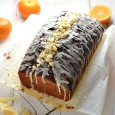 a loaf of cake sitting on top of a cutting board next to sliced oranges