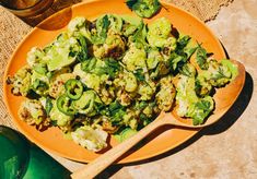 an orange plate topped with broccoli and cauliflower next to a green bottle