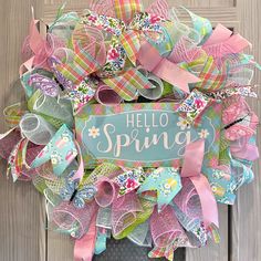 a wreath that says hello spring is hanging on a door with ribbons and bows around it